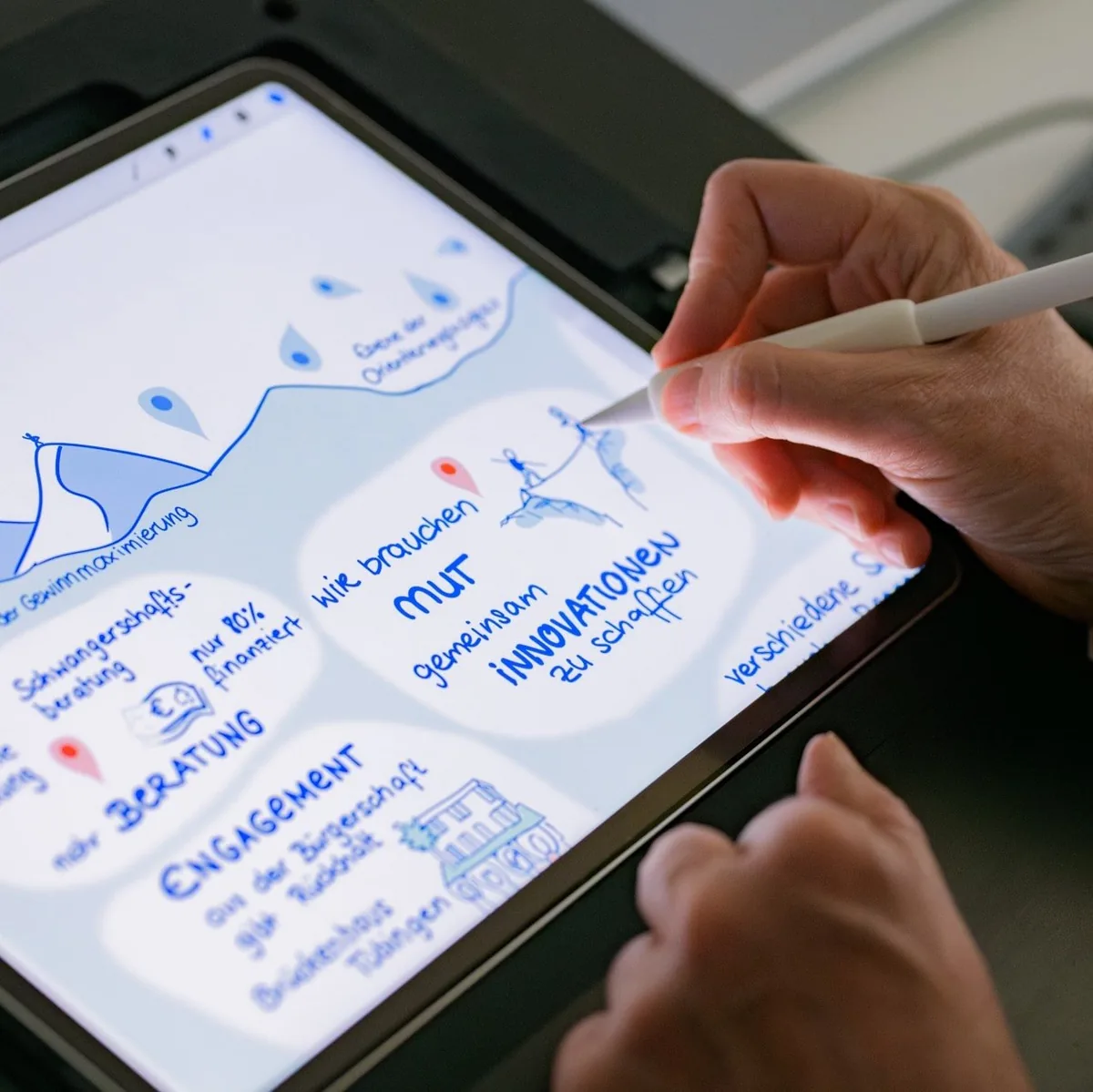 Hand mit Stift zeichnet auf einem Tablet ein Graphic Recording